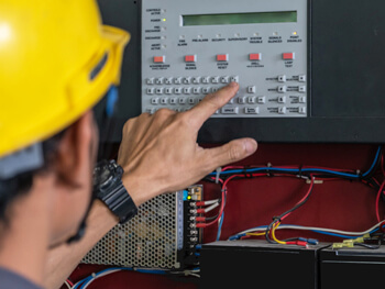 Man in a construction hat pressing buttons on a building automation control panel
